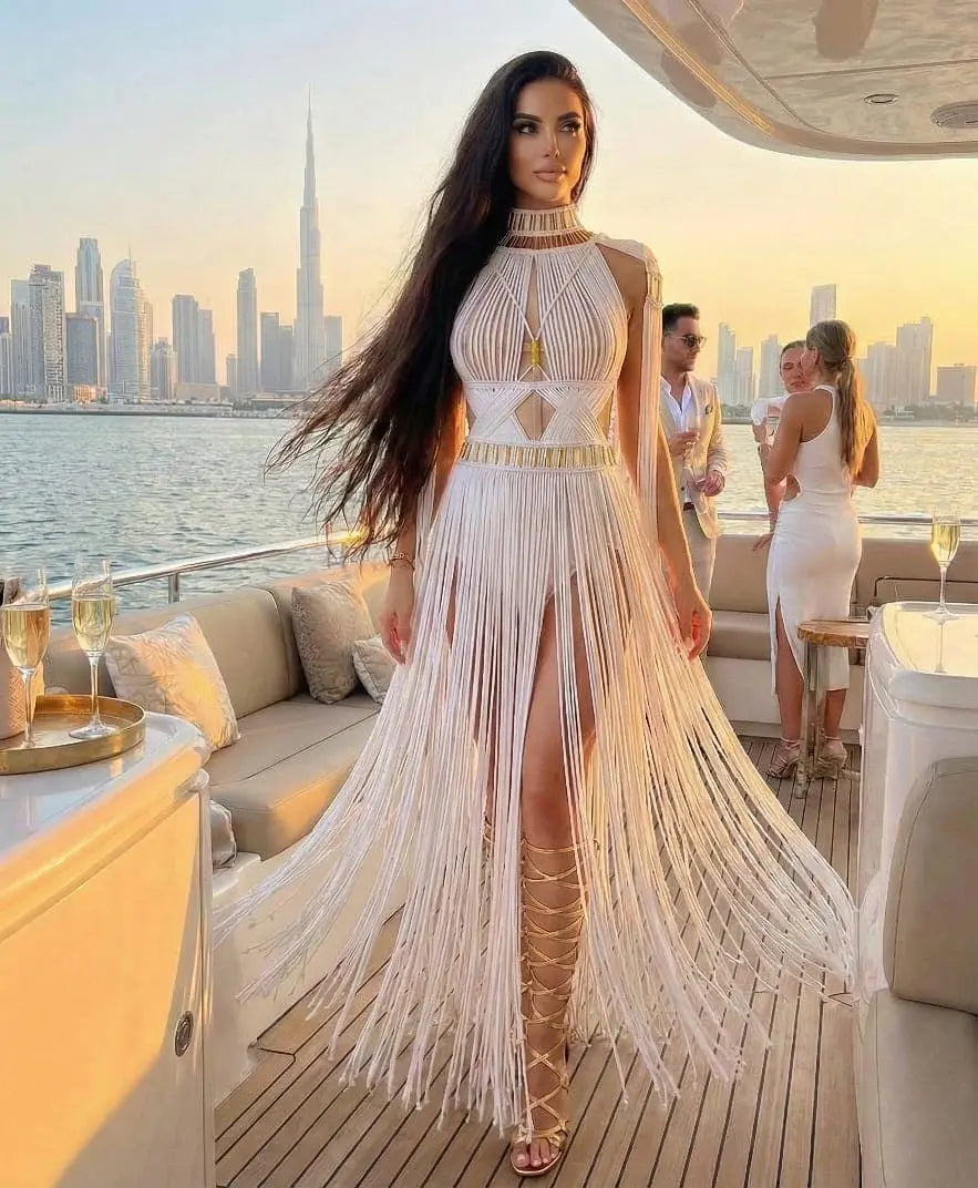 Model wearing Altysan beach and resort wear with handcrafted fringe details at a luxury yacht sunset setting.