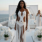 Woman in a white macramé dress on a luxurious outdoor setting with ocean view.