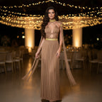 Woman in a long, elegant macrame dress standing in a decorated indoor setting with warm lighting.