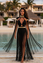 Black macramé fringe gown with gold detailing, worn at a luxury beach resort