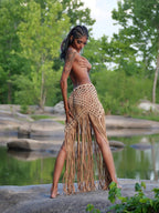 Handwoven macramé fringe maxi skirt in natural tan, worn by model in outdoor nature setting — boho wrap skirt with long fringe hem, Solaris Wrap by ALTYSAN