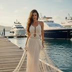 Woman in a white dress standing on a dock with yachts in the background