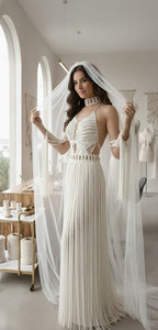 Woman in a white wedding dress with a long veil in a room with large windows.